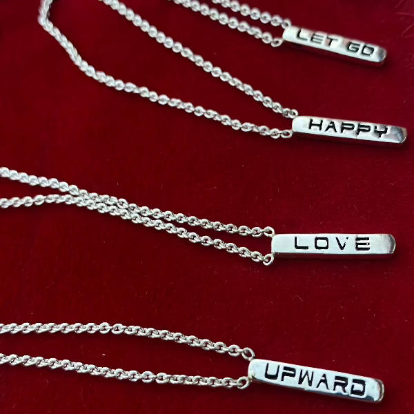 Made by hand in USA in solid sterling silver and Italian sterling silver chains. Also available in solid gold. 
These dainty necklaces have one word on one side and another on the other side. 
www.paulina jewelry.com